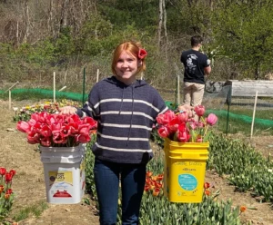 Catherine McGonagle, STEMS Co-Founder & President, holding two buckets of pink tulips